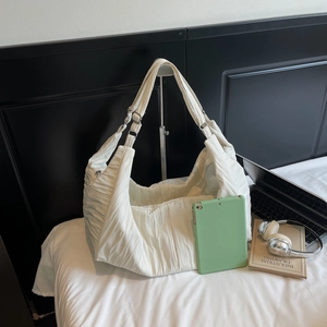 White large capacity nylon hobo bag with pleated texture and adjustable strap shown with laptop