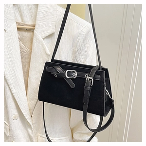 Détail du sac à bandoulière en daim noir mat avec boucle argentée sur une veste blanche