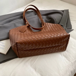 Detail of the high-quality dark brown woven leather texture on a large tote bag