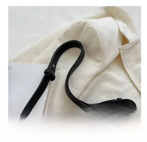 Detail van zwarte leren tas met geometrische V-stiksels en grove gouden ketting