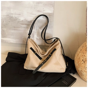Detail of beige suede tote bag featuring black leather straps and gold metal hardware