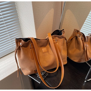 Macro detail of brown suede tote bag featuring sleek leather straps and side drawstring