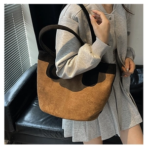 Detail of large tote bag in brown faux suede and black matte texture on model's shoulder