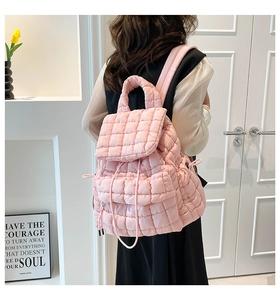 Detailed close-up of the pink quilted texture and drawstring on the padded backpack