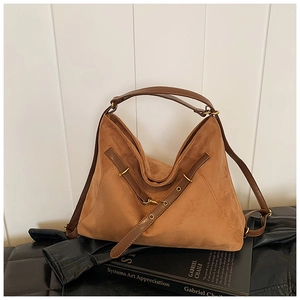 Detail of a brown suede hobo bag featuring dark leather straps and gold metal hardware