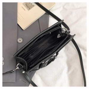 Vue intérieure du sac en cuir noir mat montrant les compartiments zippés et la doublure