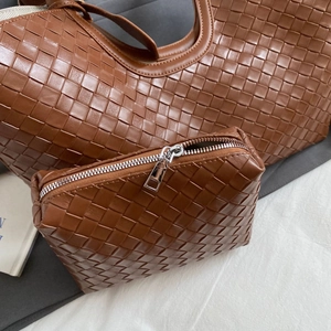 Detail of cognac leather woven tote bag set with matching small zipper pouch and texture