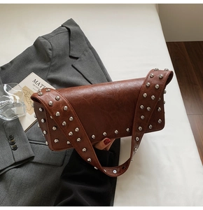 Détail d'un sac à bandoulière marron vintage avec rivets métalliques et large bandoulière