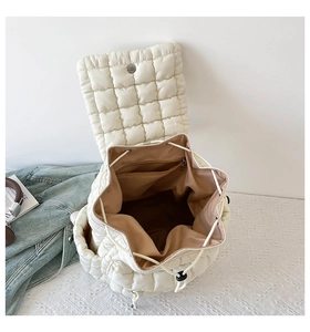 Detail of cream quilted puffer backpack showing drawstring closure and inner zipper pocket
