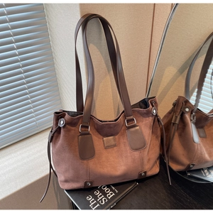 Detailed view of brown matte tote bag with side drawstrings and metal rivets