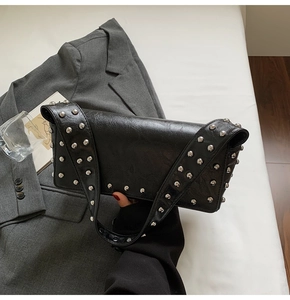 Gros plan du sac sous l'aisselle en cuir noir avec rivets argentés et bandoulière