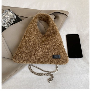 Detail of plush brown triangle handbag with leather logo label and silver metal chain