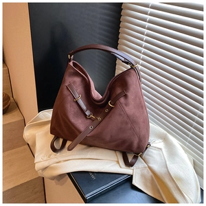 Close-up of dark brown suede tote bag with golden metal rings and leather straps