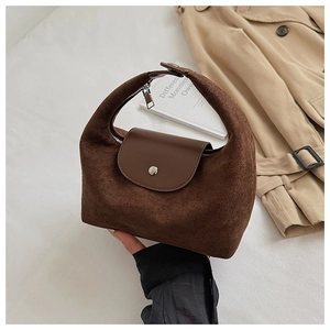 Gros plan d'un sac hobo en daim marron avec rabat en cuir lisse et fermoir magnétique argenté