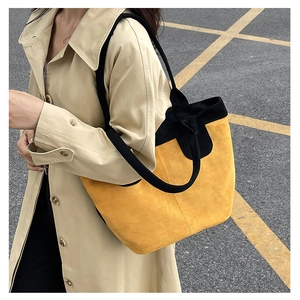Detailed shoulder view of a large yellow suede tote bag with black contrast straps