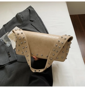 Détail du sac baguette beige avec rivets argentés et texture cuir grainé