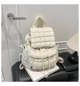 Detail of cream quilted puffer backpack featuring drawstring closure and soft texture