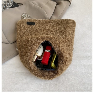 Detail showing the brown plush chain bag interior with essentials like lipstick and perfume