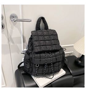 Detail of black quilted puffer backpack with drawstring closure and puffed texture