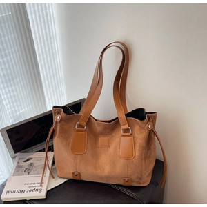 Detailed close-up of textured suede tote bag with leather straps and drawstring accents