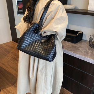 Close-up of black woven leather tote bag showing intricate weave detail and shoulder strap