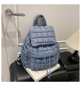 Close-up of light blue quilted puffer backpack with drawstring closure and flap