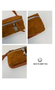 Detail of brown suede crossbody bag showing the unique silver robot zipper pull