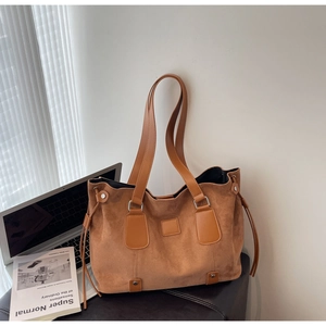 Close-up of brown suede tote bag with drawstring detail and leather strap on a desk