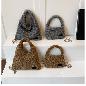 Detail of plush faux fur handbags in grey and brown with silver metal chain straps