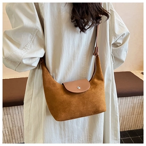 Détail de la texture en daim marron et du rabat en cuir avec bouton métallique argenté