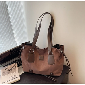 Macro detail of brown suede tote bag with leather trim and drawstring side on white background