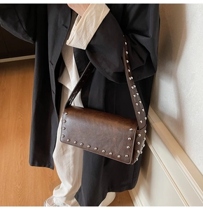 Gros plan détaillé du sac baguette vintage marron foncé avec rivets et texture cuir vieilli