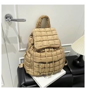 Detail of square quilted khaki puffer backpack featuring drawstring closure and metal ring
