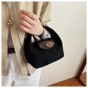 Détail du sac dumpling noir minimaliste avec texture daim et fermeture à bouton métallique