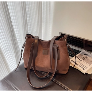 Detail of dark brown suede tote bag featuring a square patch and elegant drawstring accents