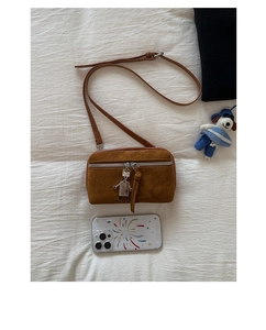 Detailed macro view of a brown suede handbag with a silver zipper and a robot charm