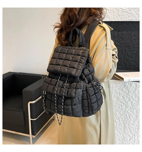 Close-up of black quilted puffer backpack with drawstring on a trench coat model