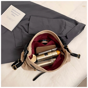 Interior detail of beige shoulder bag showing large capacity with red lining and items