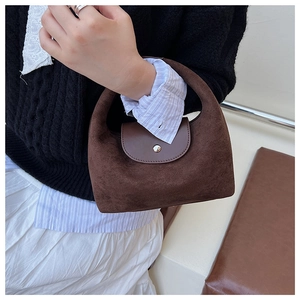 Détail d'un sac à main en daim marron foncé avec rabat en cuir lisse et boucle