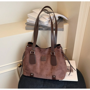 Detail of dark brown matte tote bag featuring leather straps and retro suede texture