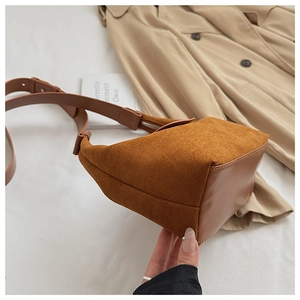 Détail du sac à bandoulière en daim marron foncé avec une large sangle élégante