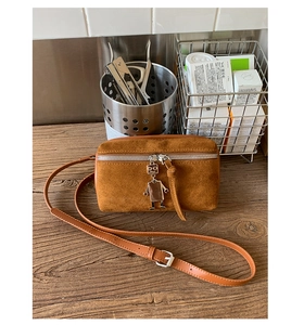 Detailed macro view of caramel suede mini bag with robot charm and silver zipper
