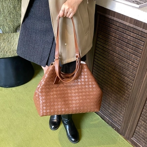 Detail shot of brown woven leather tote bag texture with elegant handle design