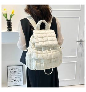 Detail of white quilted puffer backpack featuring a drawstring closure and soft texture
