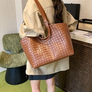 Detail of caramel woven leather tote bag with Intrecciato pattern and dual shoulder straps