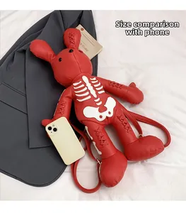Red leather bunny backpack with skull bone pattern next to a phone for size comparison