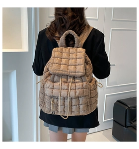 Detail of khaki quilted puffer backpack showing soft fabric texture and drawstring closure