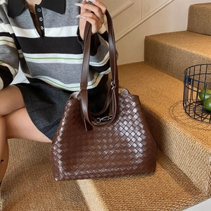 Detailed view of woven leather texture on a dark brown tote bag with metallic buckle