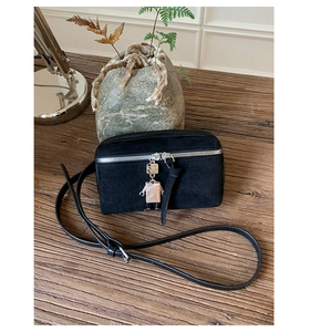 Detail of black suede crossbody bag featuring a silver zipper and robot metal charm