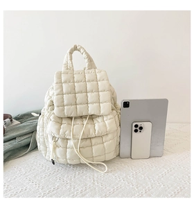 Detailed view of quilted puffer backpack in cream with front pocket and size reference